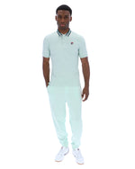 Man wearing a light green polo shirt with a small FILA logo on the chest, paired with matching joggers, against a white background