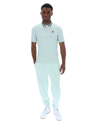 Man wearing a light green polo shirt with a small FILA logo on the chest, paired with matching joggers, against a white background