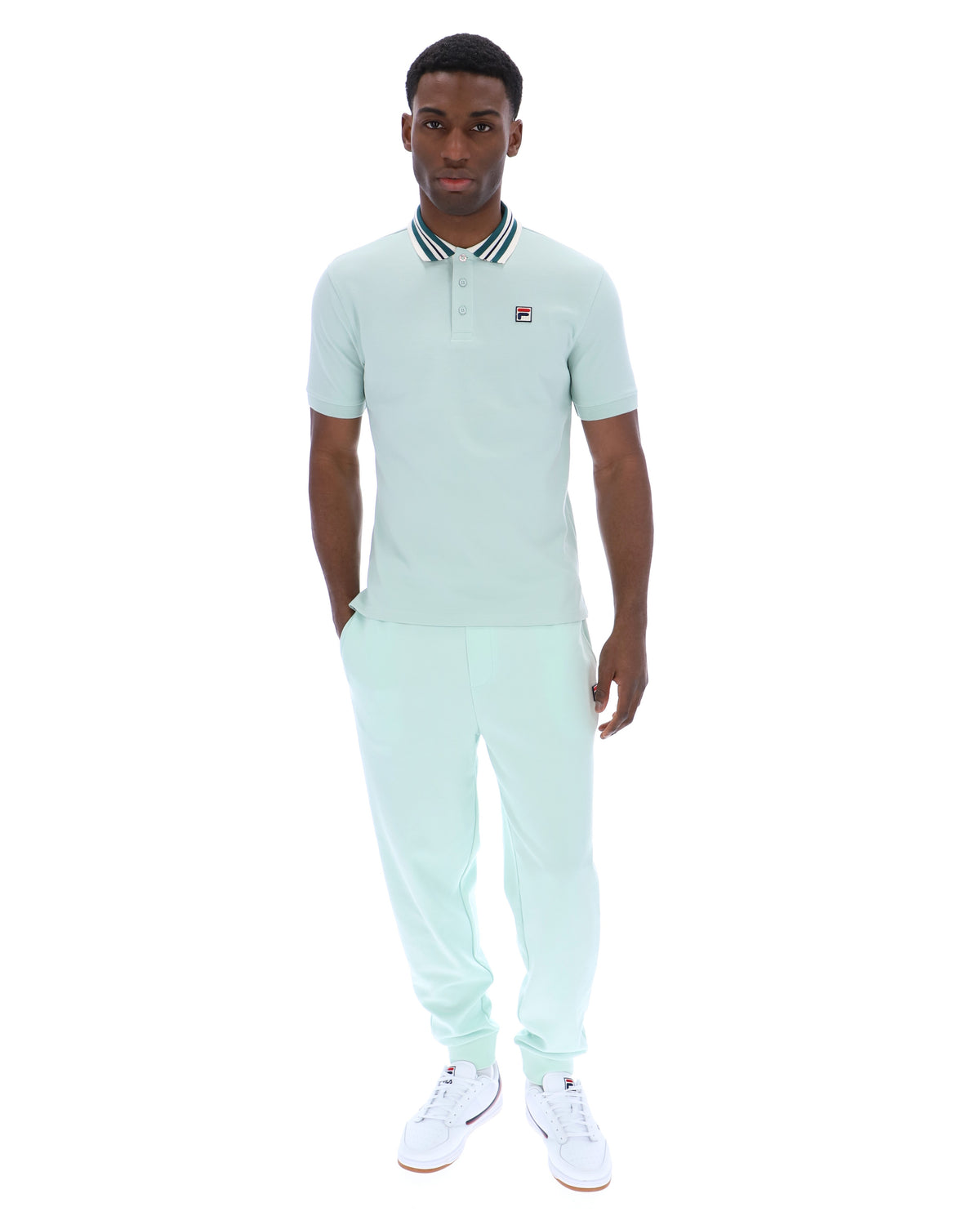 Man wearing a light green polo shirt with a small FILA logo on the chest, paired with matching joggers, against a white background