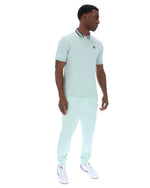 Man wearing a light green polo shirt with a small FILA logo on the chest, paired with matching joggers, against a white background