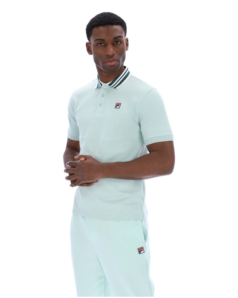Man wearing a light green polo shirt with a small FILA logo on the chest, paired with matching joggers, against a white background