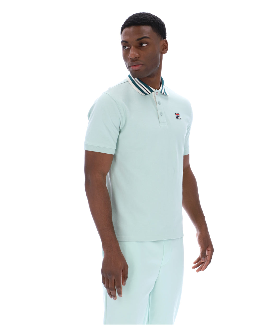 Man wearing a light green polo shirt with a small FILA logo on the chest, paired with matching joggers, against a white background