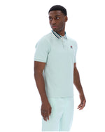 Man wearing a light green polo shirt with a small FILA logo on the chest, paired with matching joggers, against a white background
