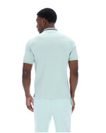 Man wearing a light green polo shirt and pants on a white background