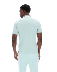 Man wearing a light green polo shirt and pants on a white background