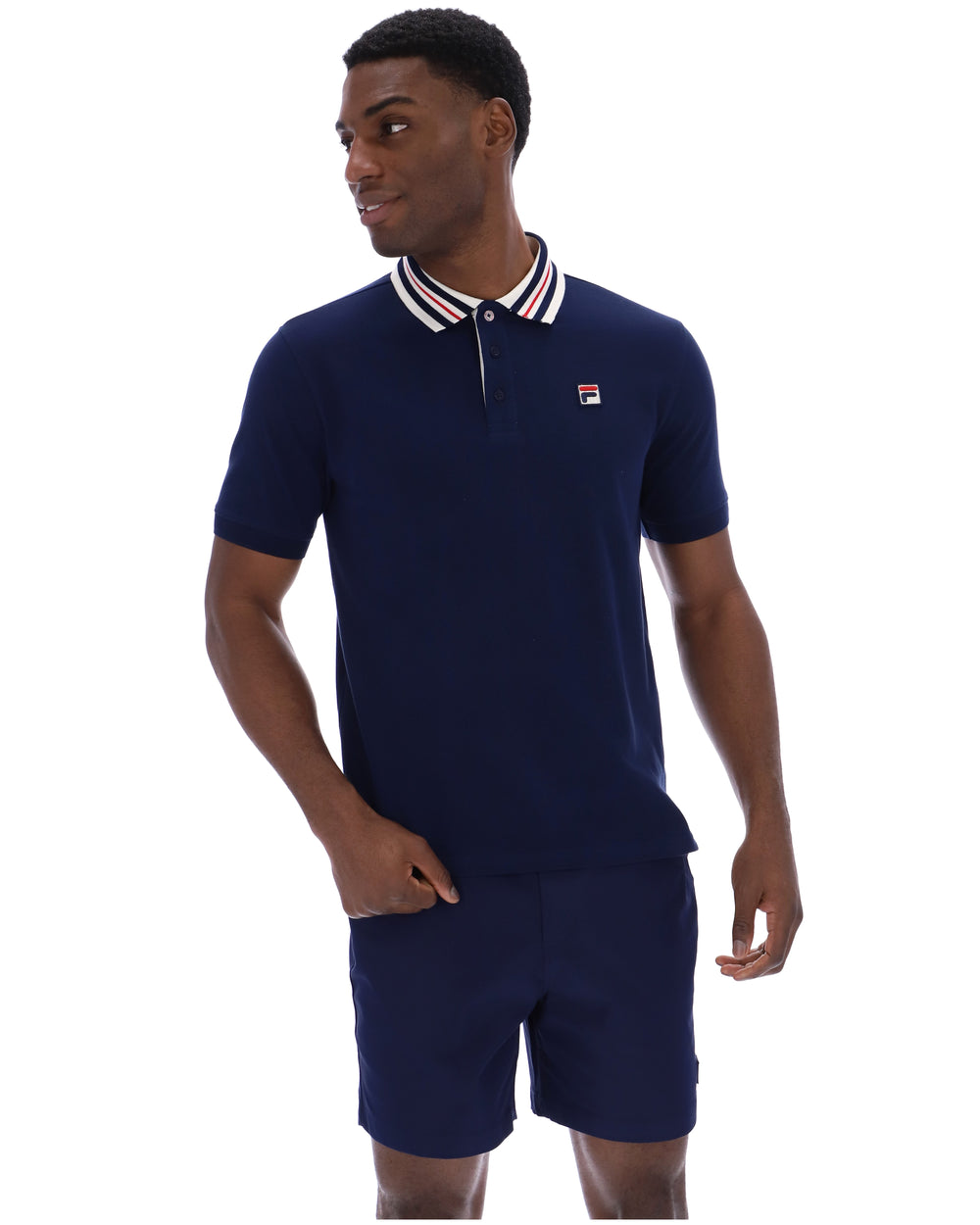 Man wearing a navy polo shirt and shorts with a visible brand logo on a white background