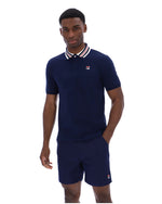 Man wearing a navy blue polo shirt and shorts with a brand logo on a white background