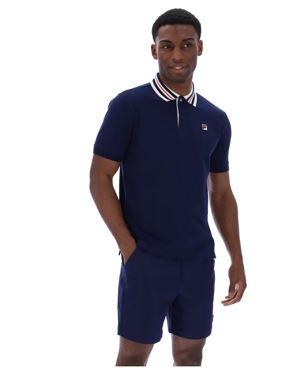 Man wearing a navy blue polo shirt and shorts set on a white background