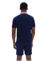 Man wearing a navy blue polo shirt and shorts set on a white background