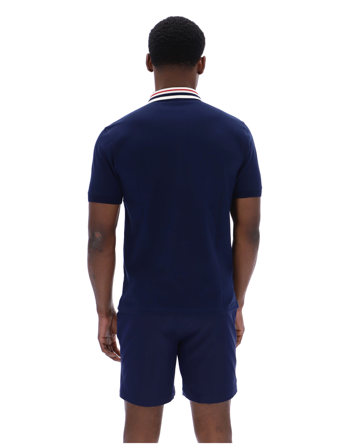 Man wearing a navy blue polo shirt and shorts set on a white background