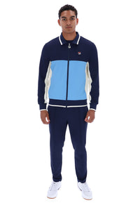 A man modeling a navy blue, light blue, and white color-blocked track suit with white sneakers against a plain white background.