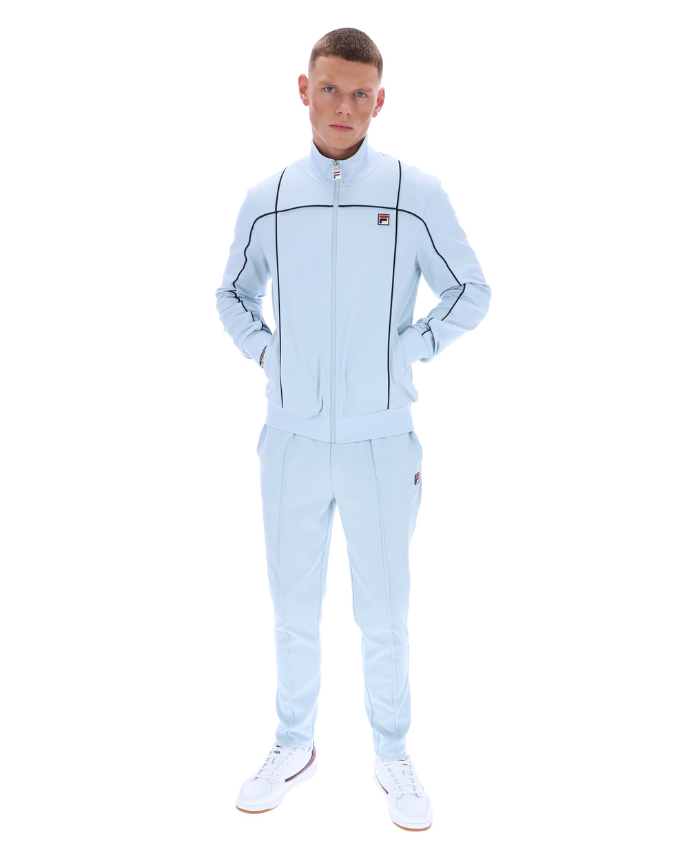 Man wearing a light blue tracksuit with a brand logo on a white background