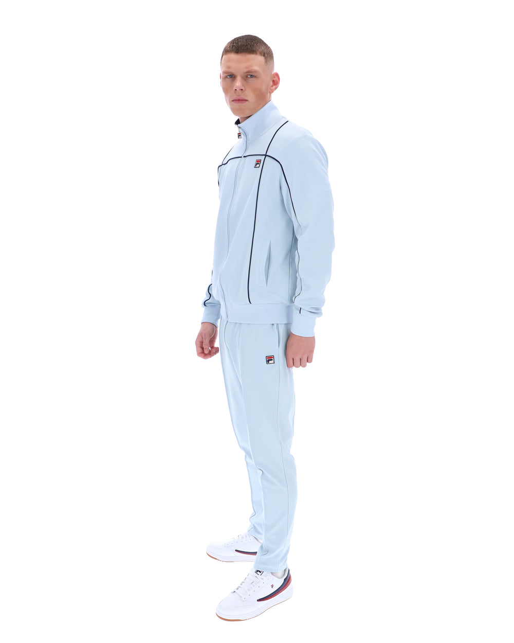 Man wearing a light blue tracksuit with a brand logo on a white background