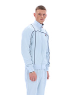 Man wearing a light blue tracksuit with a logo on a white background
