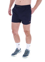 A person wearing black Artoni Swim Shorts with a drawstring waistband and the FILA logo on the leg, paired with white socks and grey sneakers.