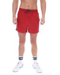 Red swim shorts worn by a person on a white background