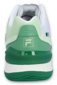 A white tennis trainer with green accents and the FILA logo on the heel.
