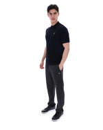 Man wearing a black polo shirt with a small FILA logo on the chest, paired with black FILA joggers, against a white background