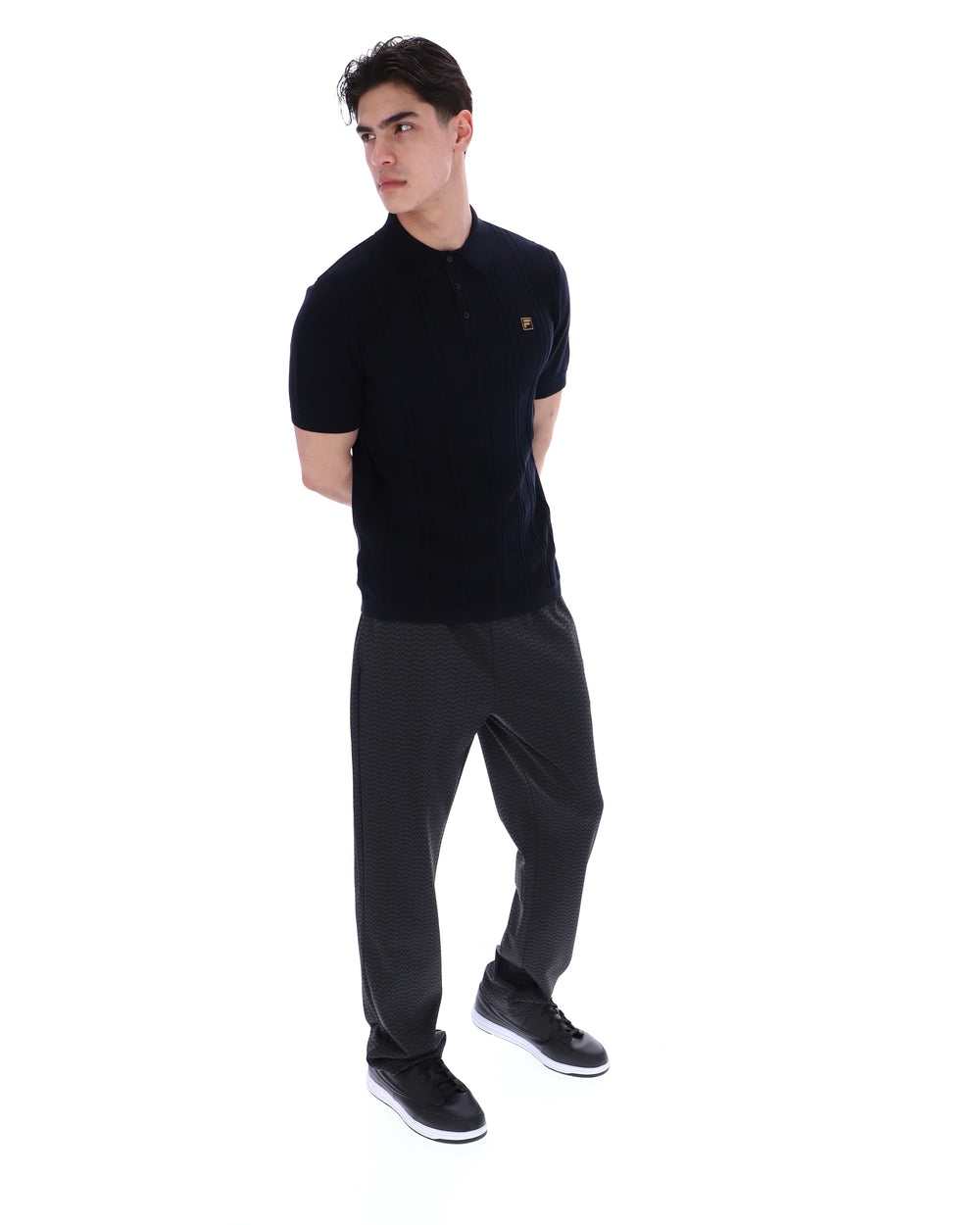 Man wearing a black polo shirt with a small FILA logo on the chest, against a white background