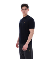 Man wearing a black polo shirt with a small FILA logo on the chest, paired with black FILA joggers, against a white background