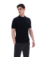 Man wearing a black polo shirt with a small FILA logo on the chest, paired with black FILA joggers, against a white background