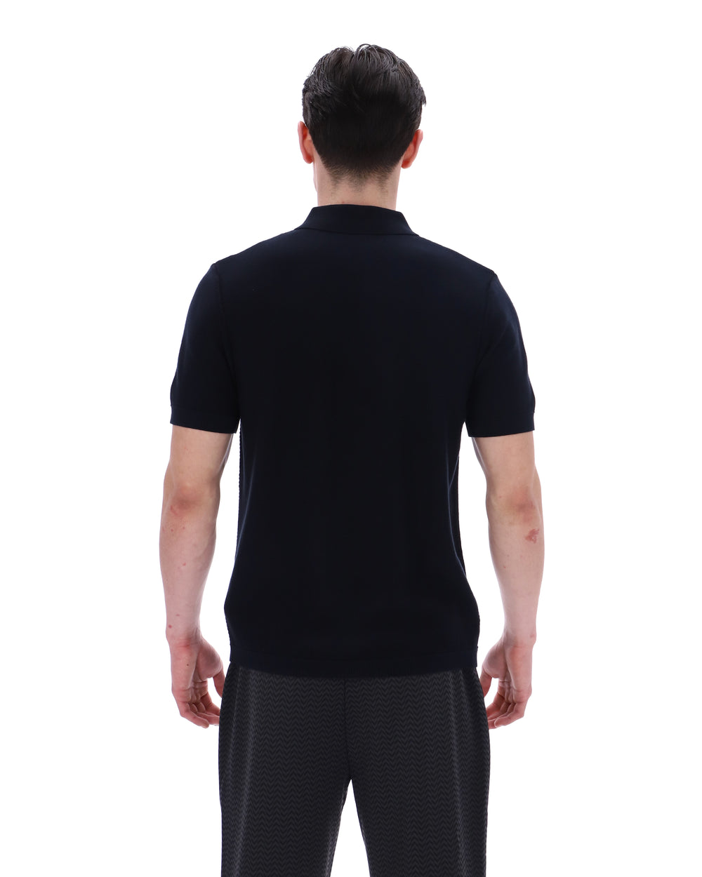 Man wearing a black polo shirt and dark pants on a white background