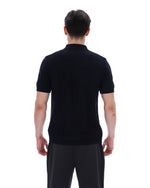 Man wearing a black polo shirt and dark pants on a white background