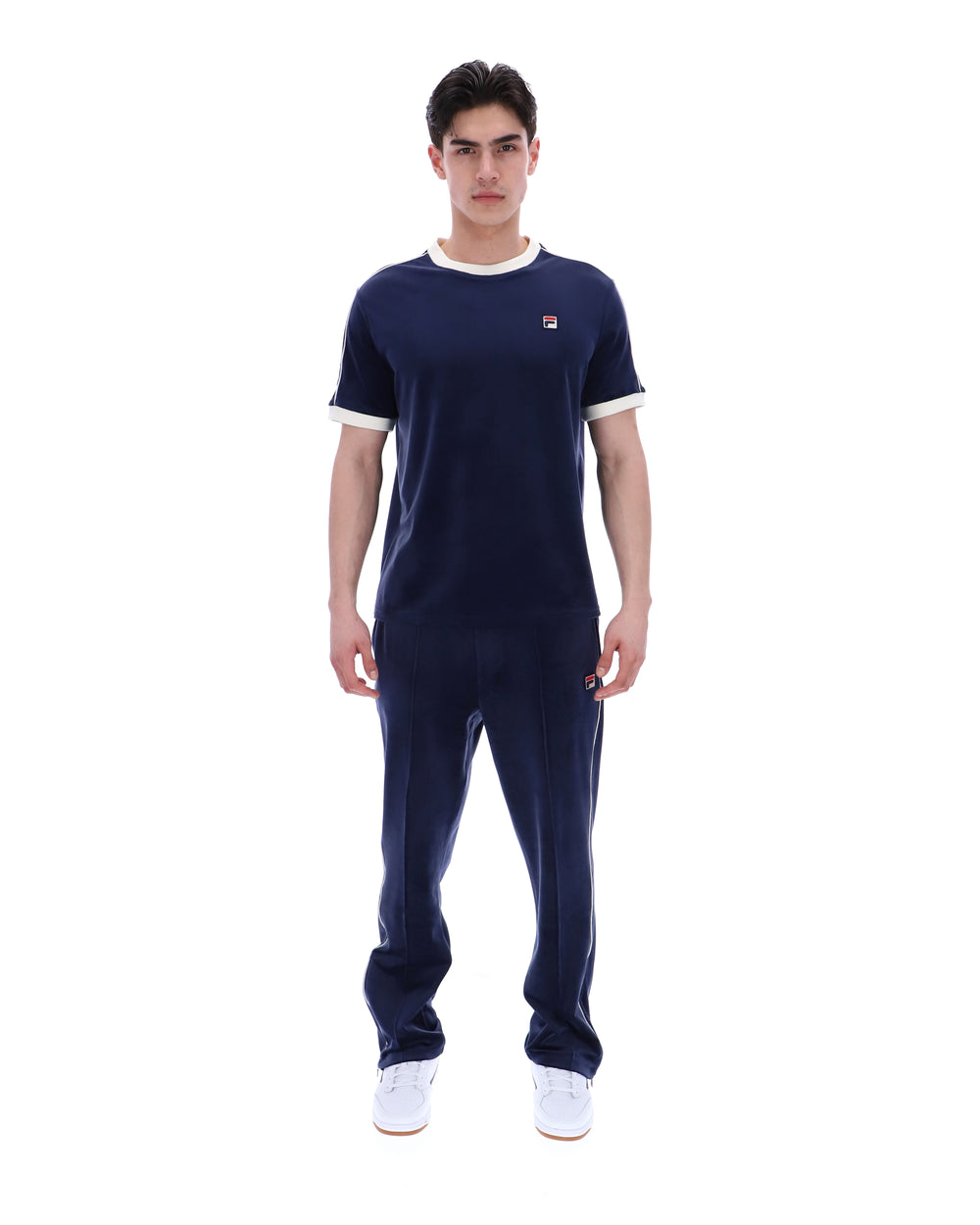 Man wearing a navy tracksuit with white accents on a white background