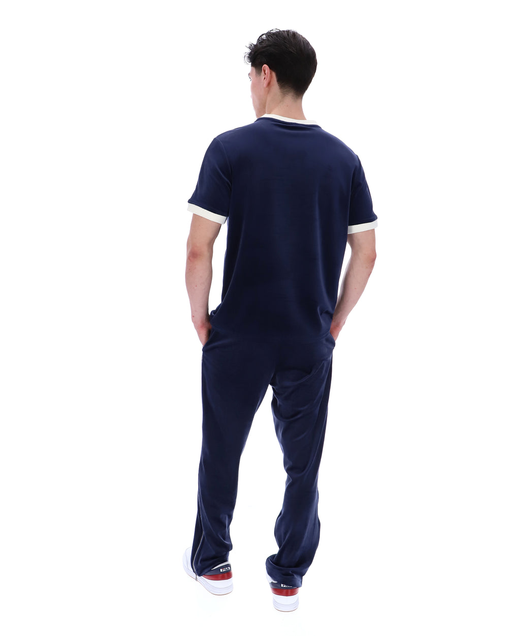 Man wearing a navy blue outfit with white trim on a white background