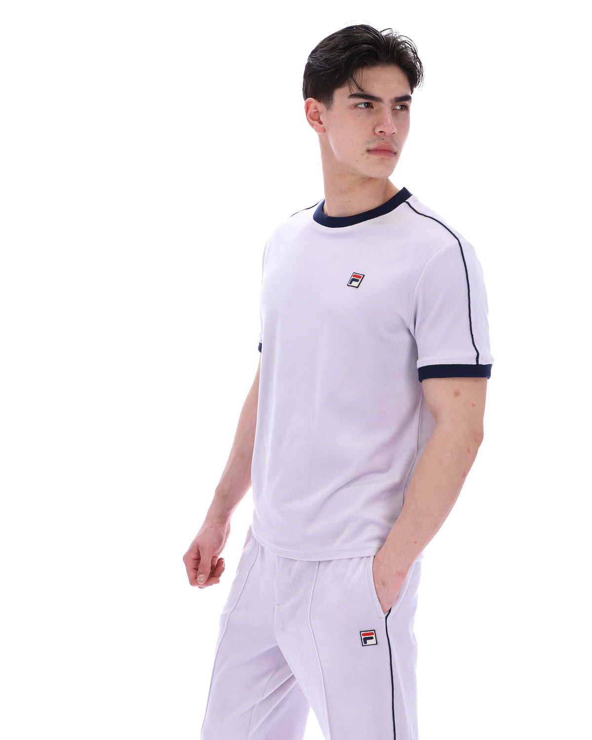 Person wearing a lilac t-shirt with a FILA logo, paired with matching joggers, on a white background