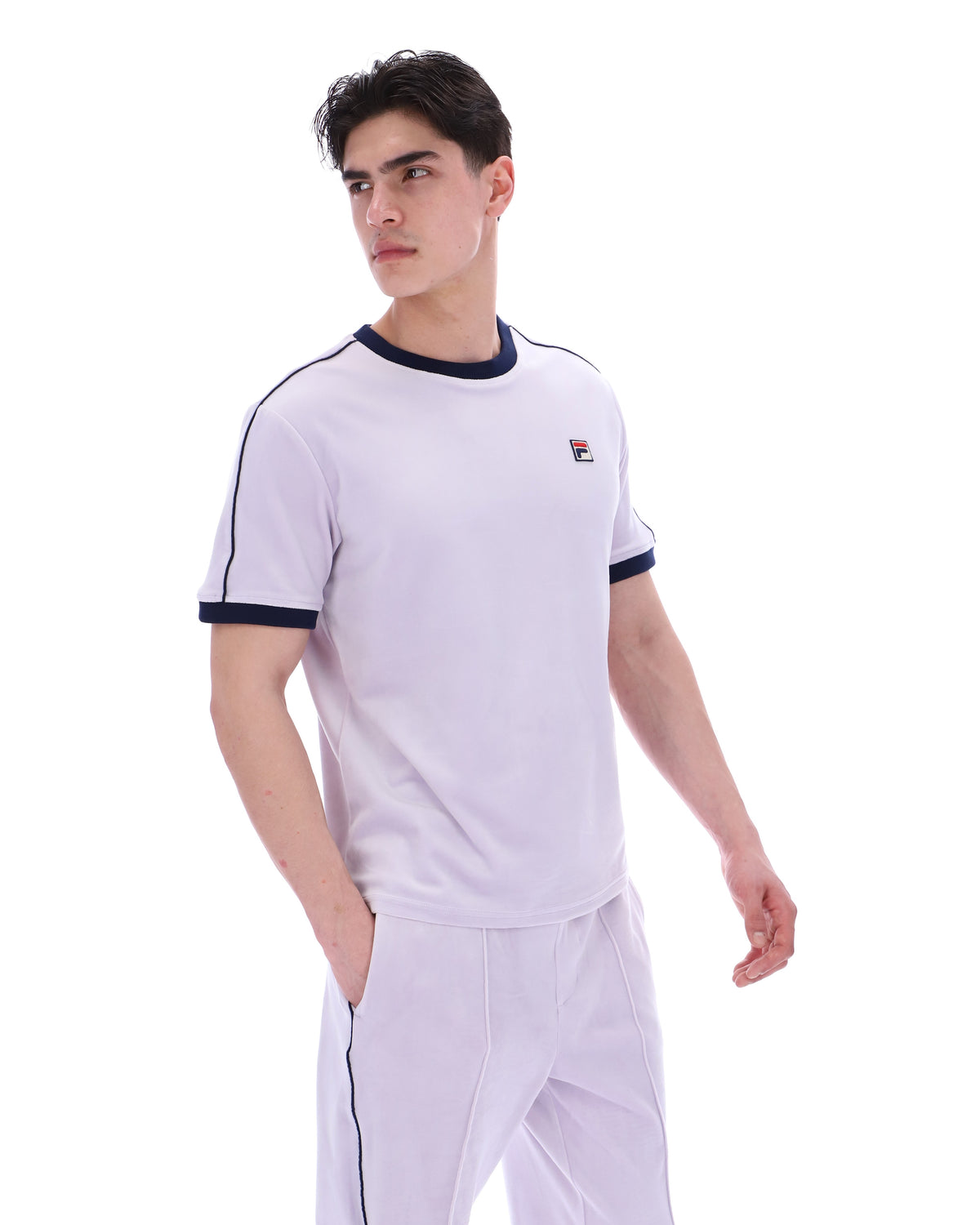 Person wearing a lilac t-shirt with a FILA logo, paired with matching joggers, on a white background