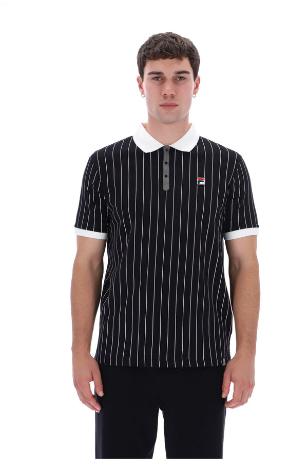 A man wearing a black short-sleeve polo shirt with thin white vertical pinstripes, a white collar, and a small red and white Fila logo on the chest, photographed against a plain white background.