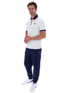 A man modeling a white short-sleeve polo shirt with thin navy vertical pinstripes, a navy collar, and a small red-and-white logo on the chest, paired with navy jogger pants and white sneakers, against a plain white background.