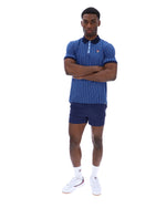 Man wearing a blue striped polo shirt and shorts with white socks and shoes on a white background