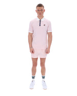 Man wearing a pink polo shirt and shorts set on a white background