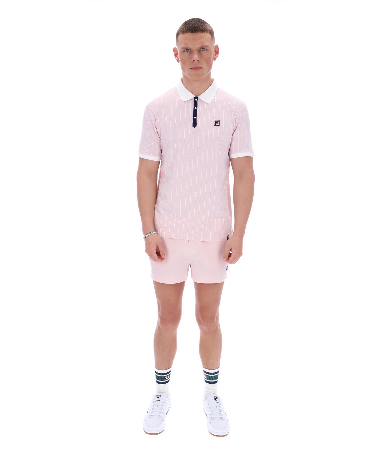 Man wearing a pink polo shirt and shorts set on a white background