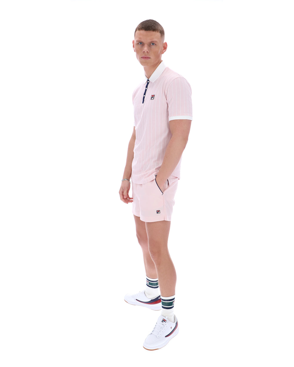 Man wearing a light pink tennis outfit with a white background