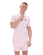 Man wearing a light pink polo shirt and shorts with a small logo on a white background