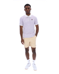 Man wearing a light purple polo shirt and beige shorts on a white background