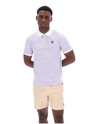 Man wearing a lilac striped polo shirt with a FILA logo on the chest, paired with beige shorts on a white background