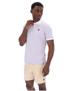 Man wearing a lilac striped polo shirt with a FILA logo on the chest, paired with beige shorts on a white background