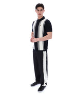 Person wearing a black and white striped shirt with a FILA logo on the chest and black pants on a white background