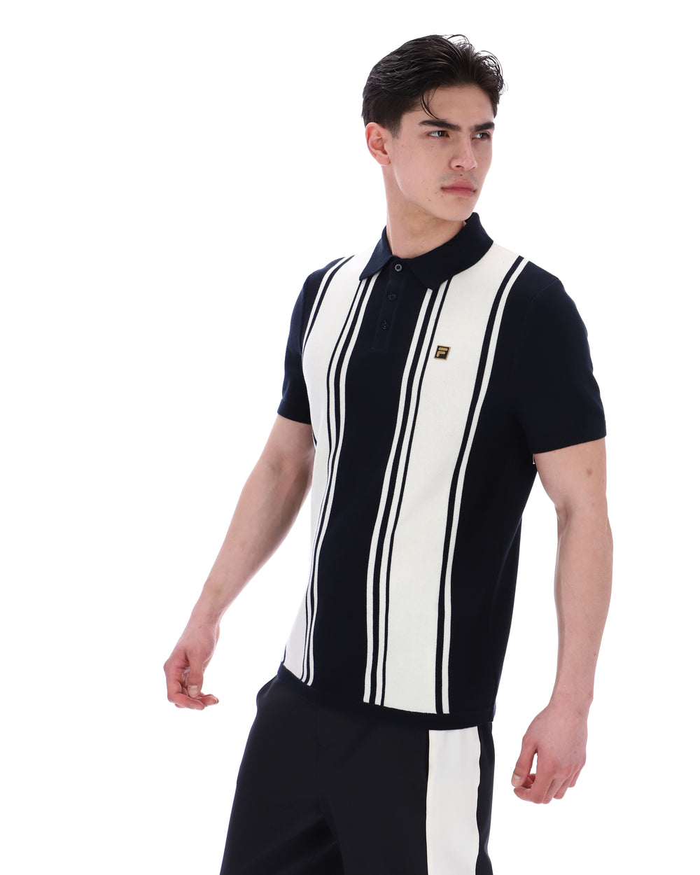 Person wearing a black and white striped shirt with a FILA logo on the chest and black pants on a white background