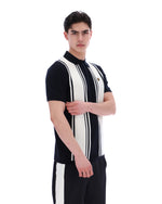 Person wearing a black and white striped shirt with a FILA logo on the chest and black pants on a white background