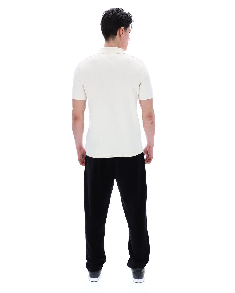 Man wearing a white polo shirt and black pants on a white background