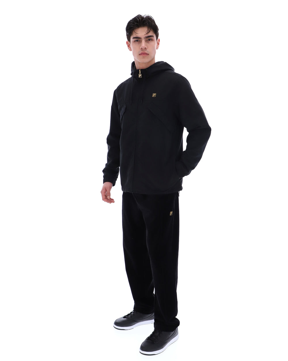 Person wearing a black hoodie and pants with a brand logo on a white background