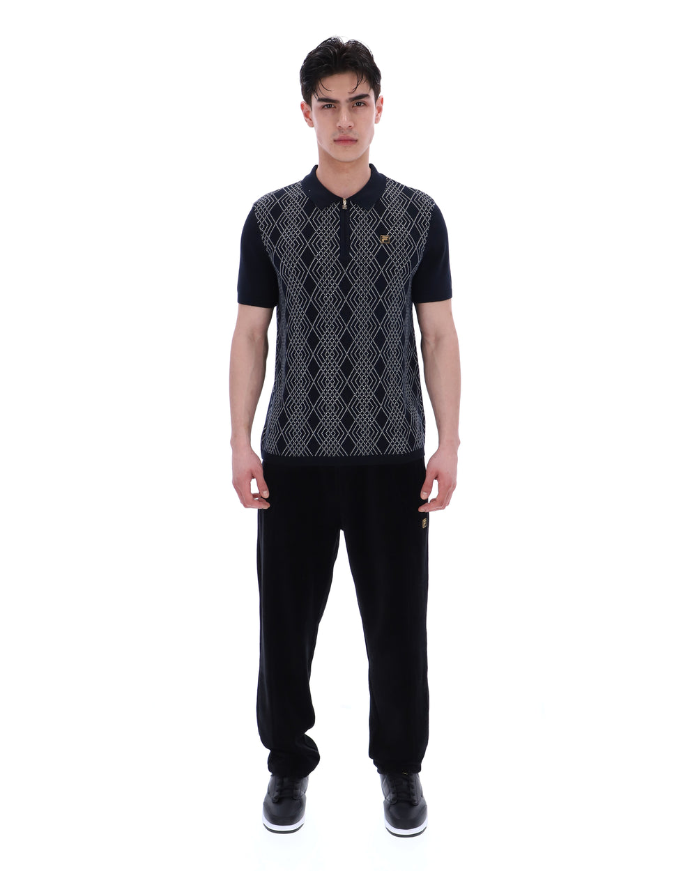 Man wearing a black and grey patterned shirt with black pants on a white background