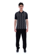 Man wearing a black and grey patterned shirt with black pants on a white background