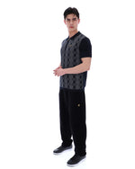 Man wearing a black and grey patterned shirt with black pants on a white background
