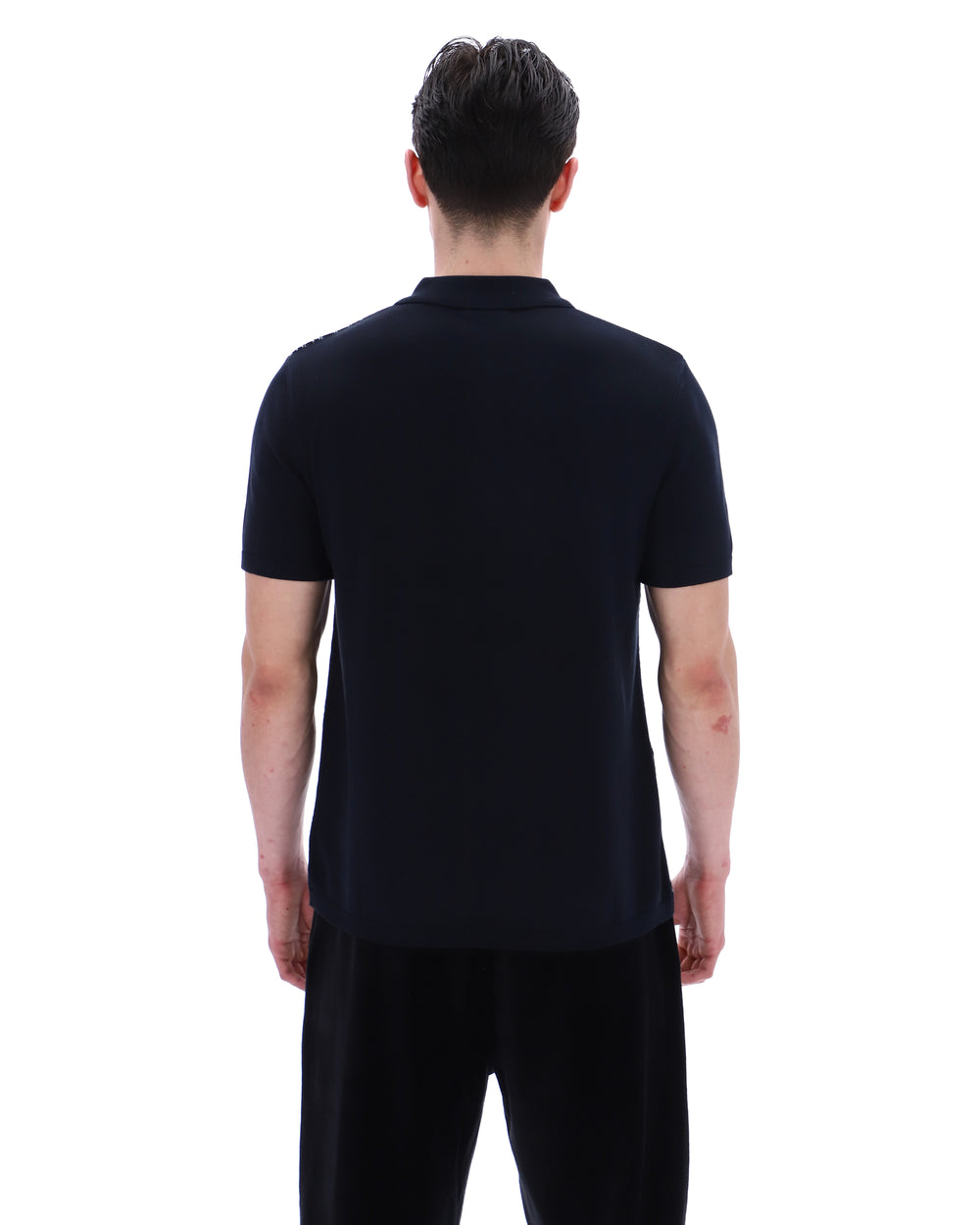 Person wearing a black polo shirt and pants on a white background